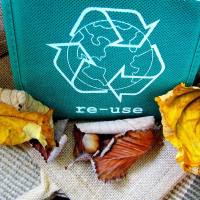 Photographie d'un sac en tissu portant l'inscription "re-use" accompagnée du logo du recyclage